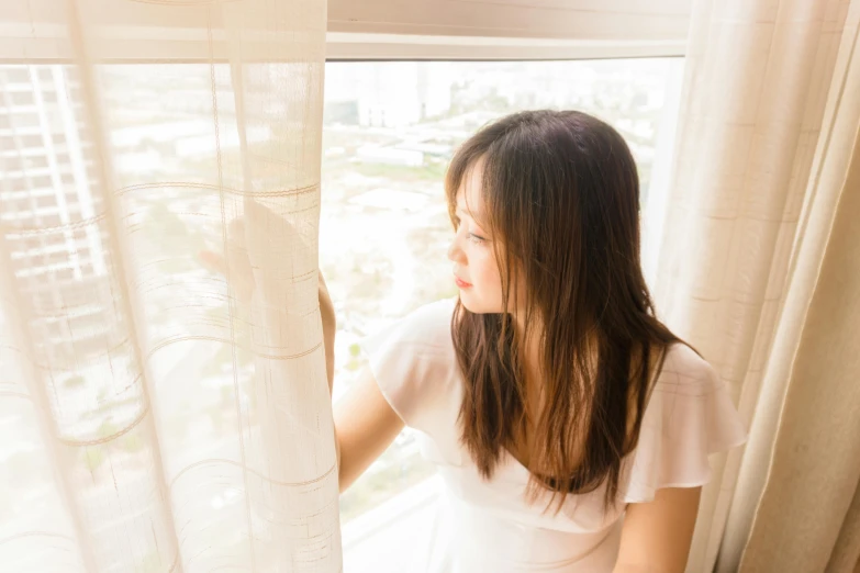 a woman looking out the window at a city outside