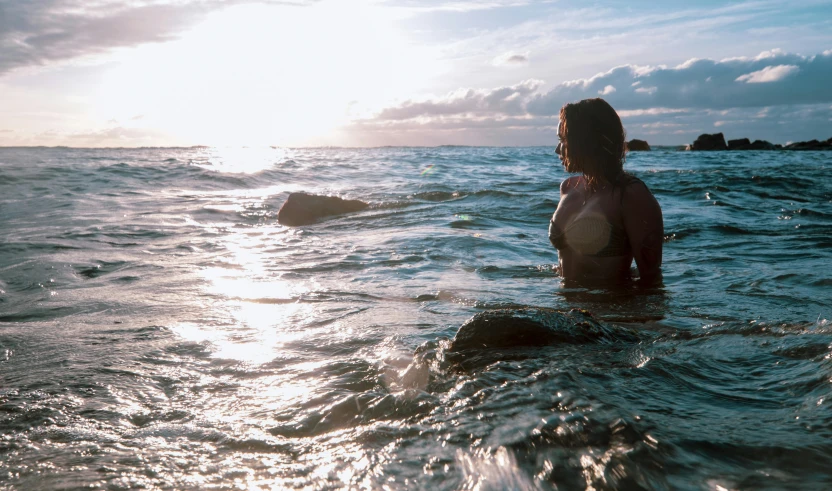 a woman wearing a wet suit standing in the ocean