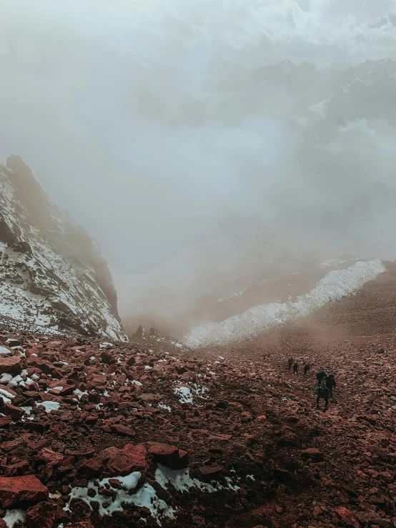 a person walks in a barren landscape as fog rises up into the sky