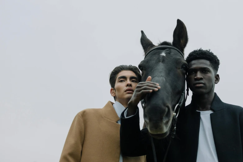 two men in matching outfits holding onto the neck of a horse