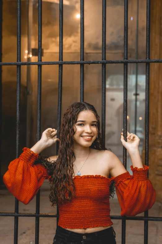 a woman holding a cigarette behind a metal fence