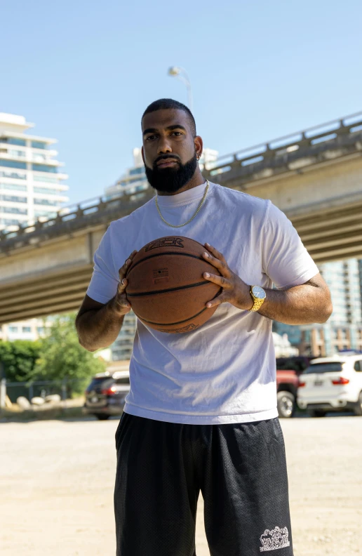 man standing in parking lot holding basketball on his hands