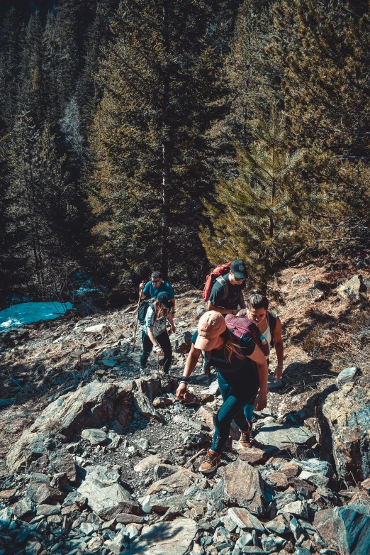 three people climbing up rocks in a canyon