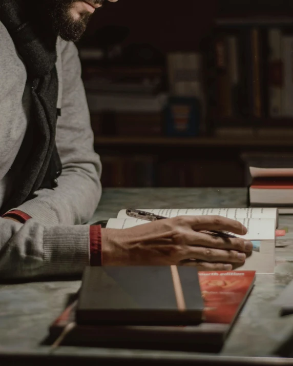 a man is sitting at a table using a book