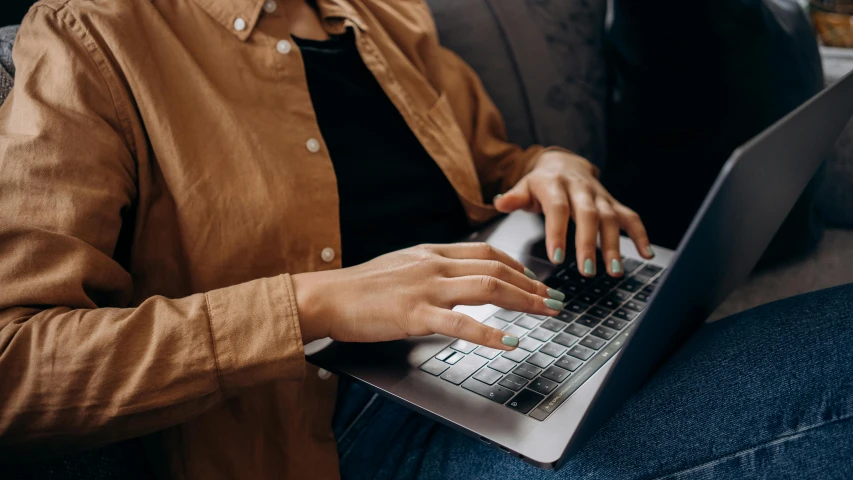 a woman is using a lap top on a sofa