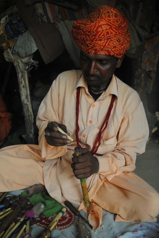 a man sits on the ground working with yarn