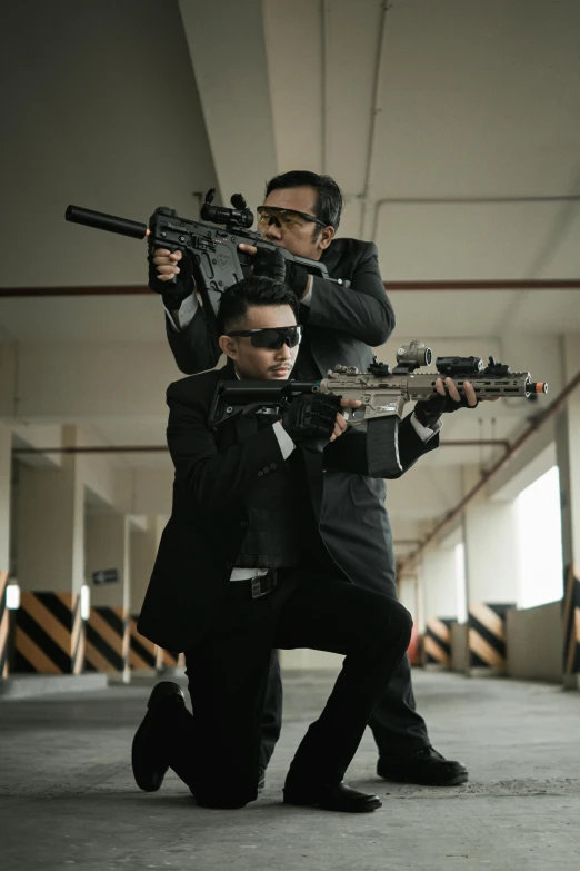 two people wearing black clothes, holding guns with sunglasses on