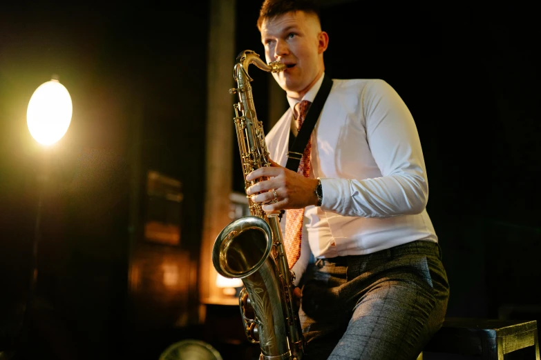 a man in a tie and vest playing on a saxophone