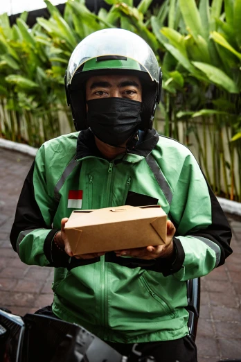 a man in a mask sitting on a motorcycle holding a box
