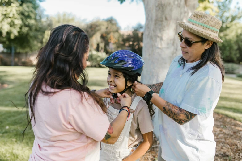 a woman helping a little girl fix her helmet on