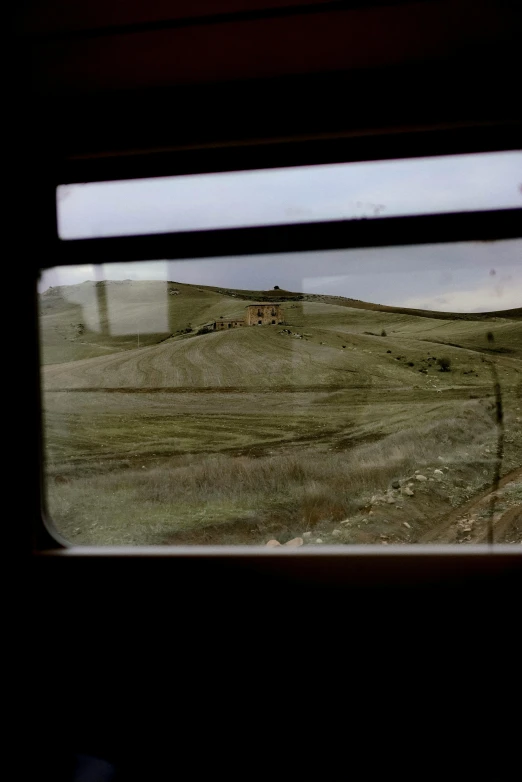 a picture looking out a train window at an abandoned farm and house