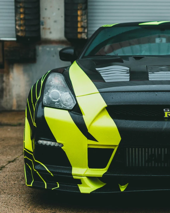 a black and yellow car in front of a garage