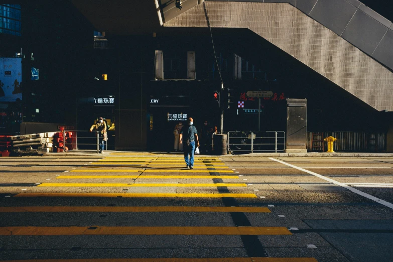 people walk down a pedestrian crossing on a city street