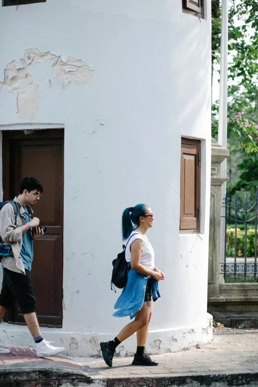 a woman in a blue skirt is walking near a white building