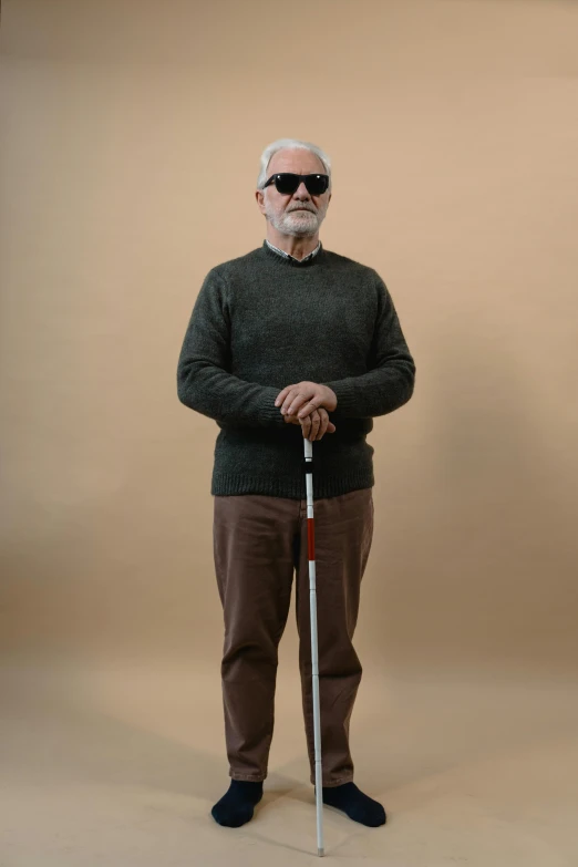 an older man in a sweater and pants posing with a cane