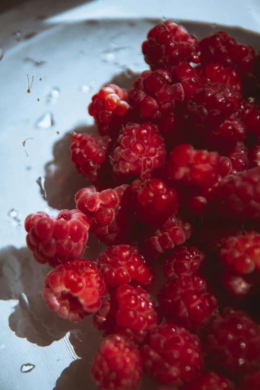 a bunch of raspberries inside a glass bowl