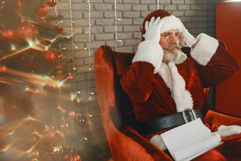 a santa clause sitting in a chair talking on a cellphone