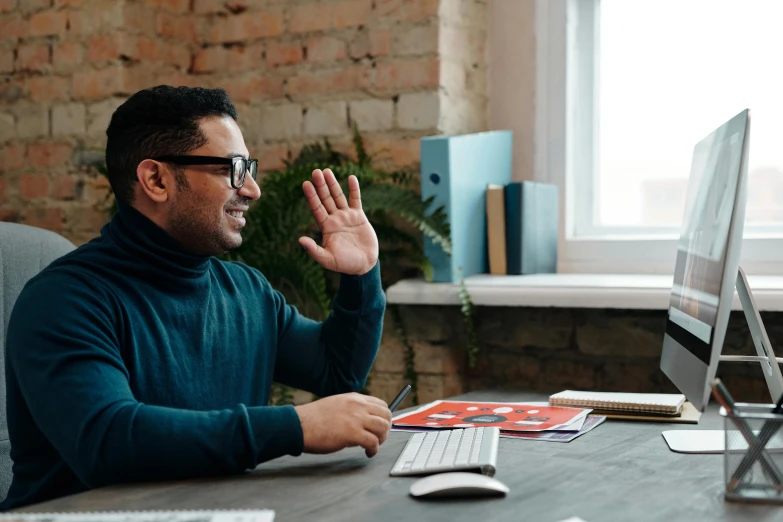 a man sitting at his desk using his hands to clap