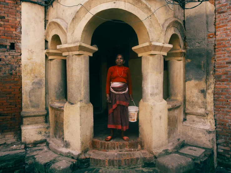 a woman in a red sweater stands outside a building