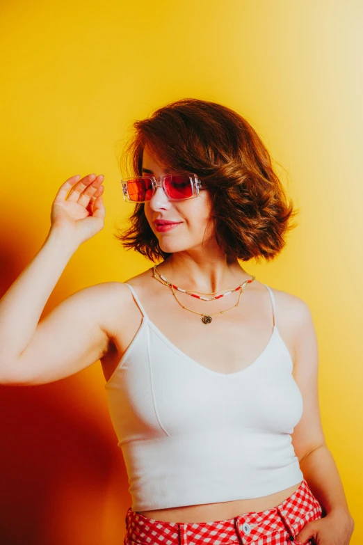 a woman in glasses posing against a yellow background