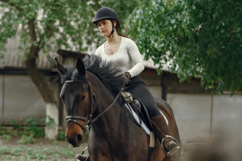 a girl riding a brown horse and making it appear she is wearing a hat