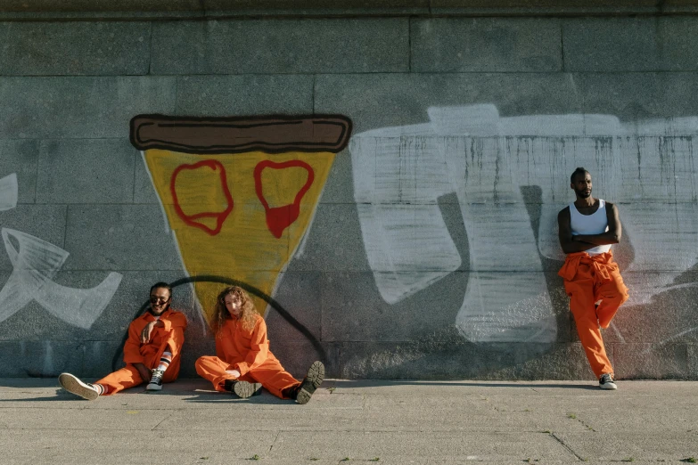 two women with orange pants posing near graffiti