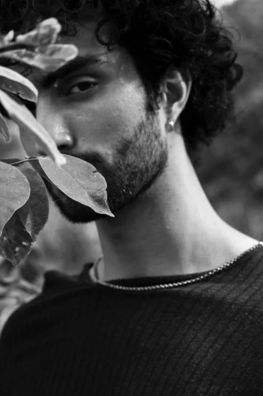 a man wearing a black sweater holding onto a plant