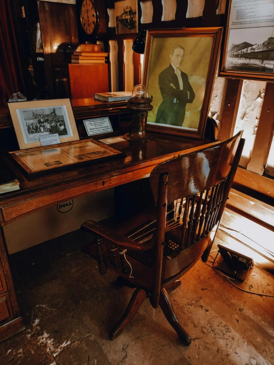 antique desk with two framed pograph on it, and wooden chair