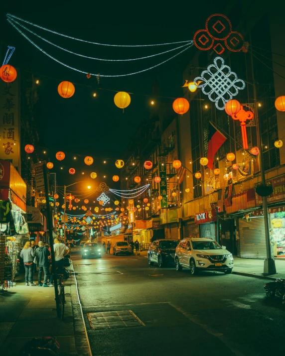 a street scene with lots of orange lanterns hanging over it