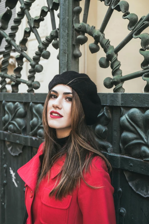 a young woman is standing next to a green fence