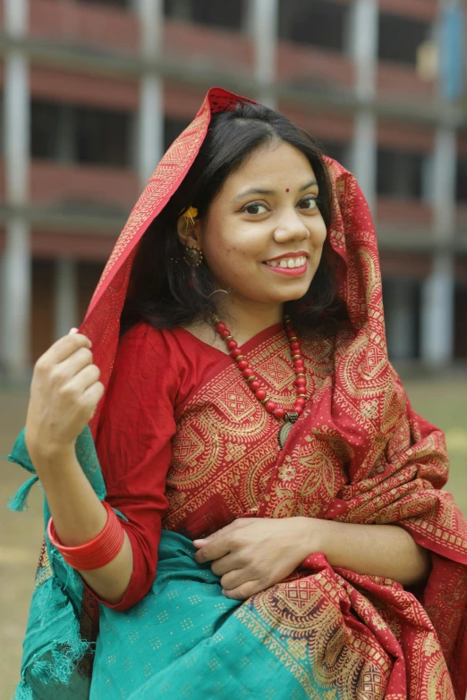 woman with red and blue sari in front of large building