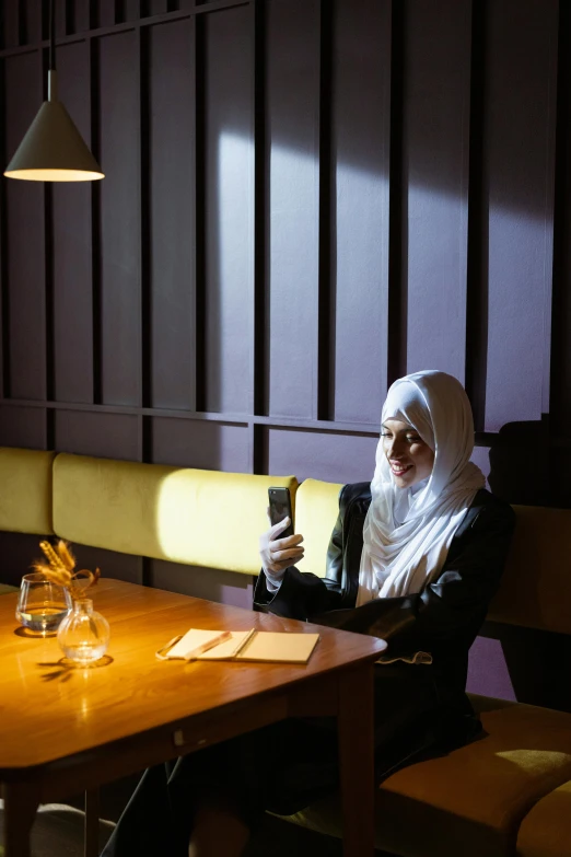 the woman is sitting alone on the table using her cell phone