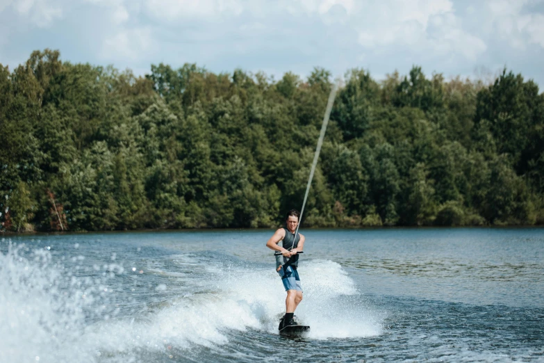 man standing still holding ropes on the water using wake board