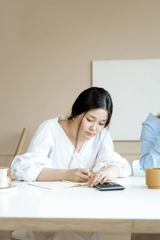 two women sitting at a table in front of a tablet