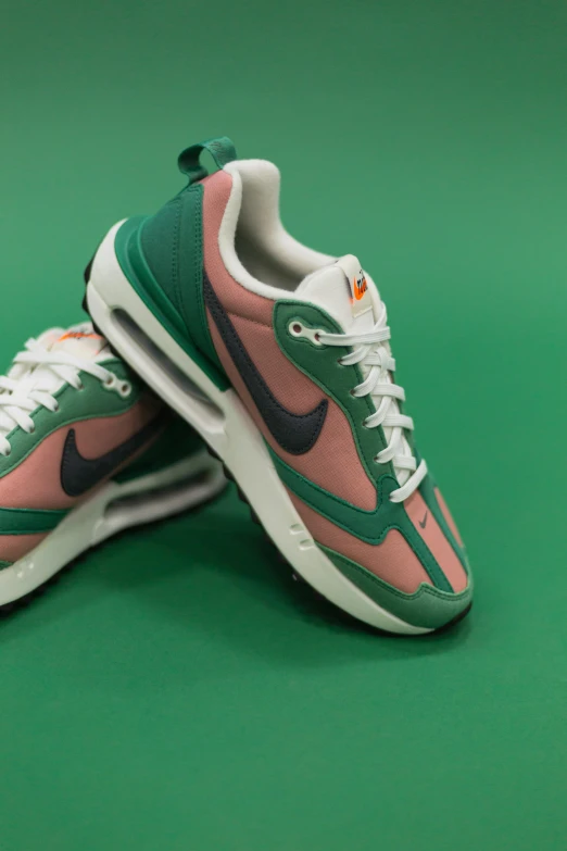 a pair of nike running shoes sit on a green background