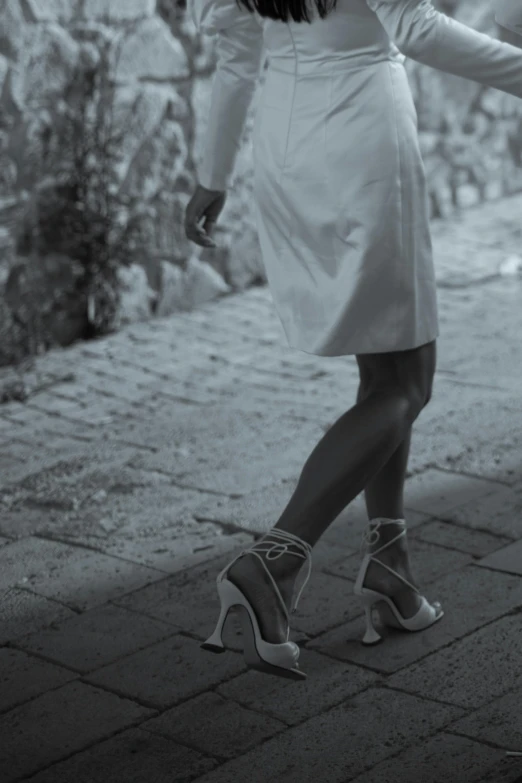 a lady with high heels walking down a sidewalk