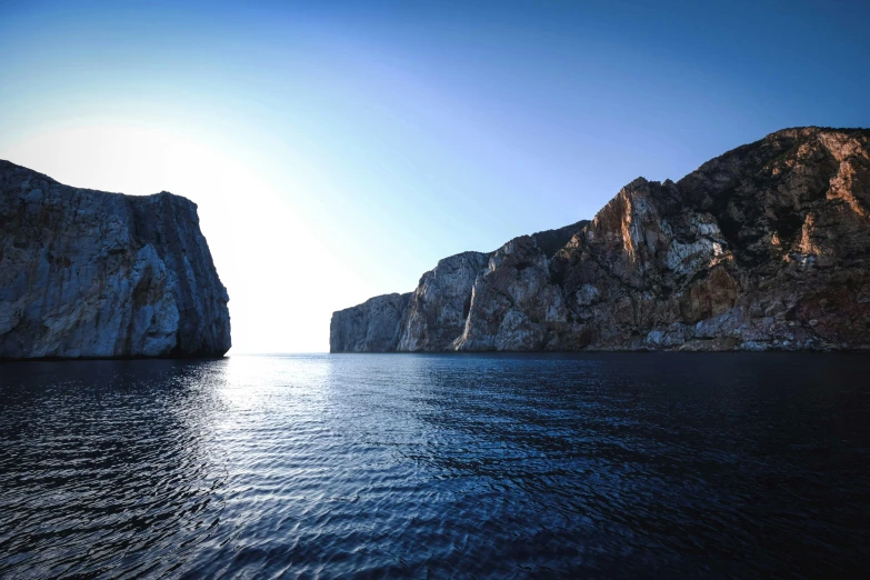 several large rocks on a blue ocean and clear sky