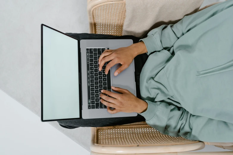 a person sitting down using a laptop on their lap