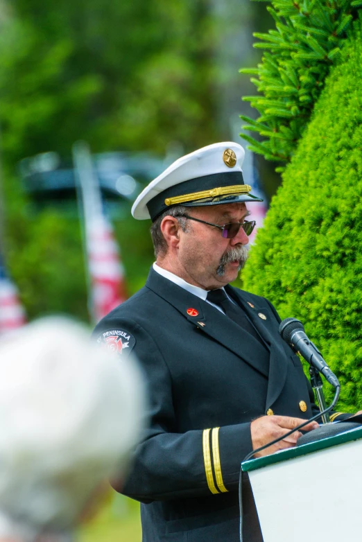 a military officer speaking into a microphone at a ceremony