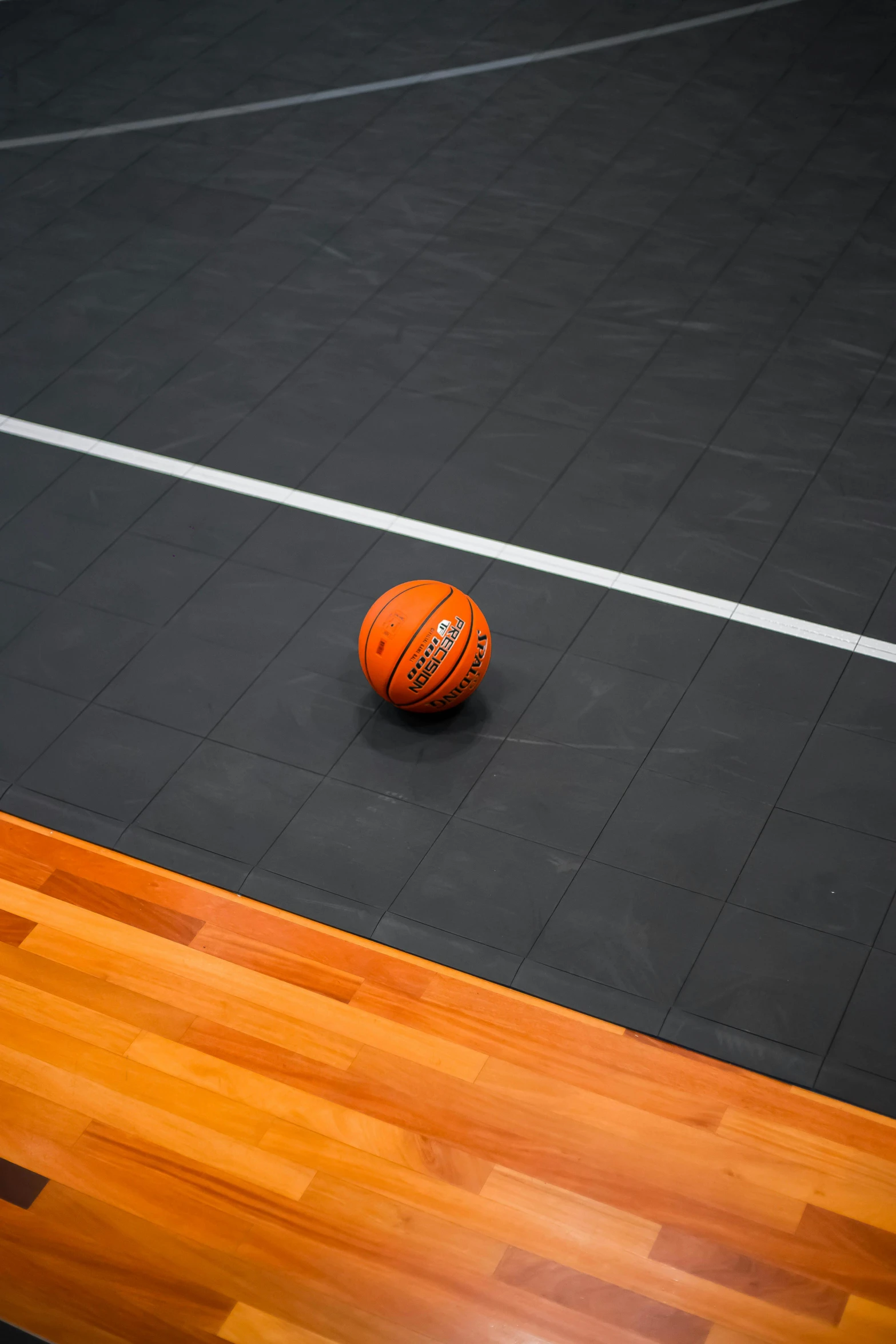 a basketball lying on the floor, in an indoor court