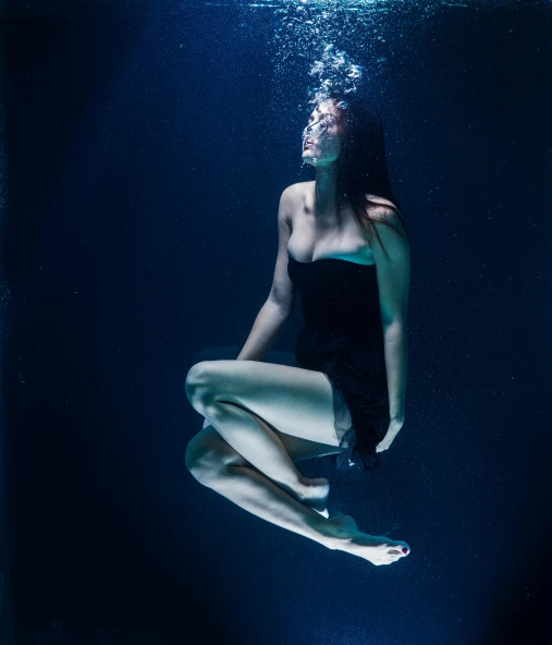 a woman in a bodysuit floating under water