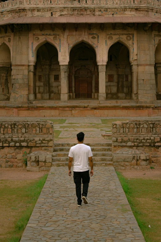 a man is walking down a brick walkway outside of a building