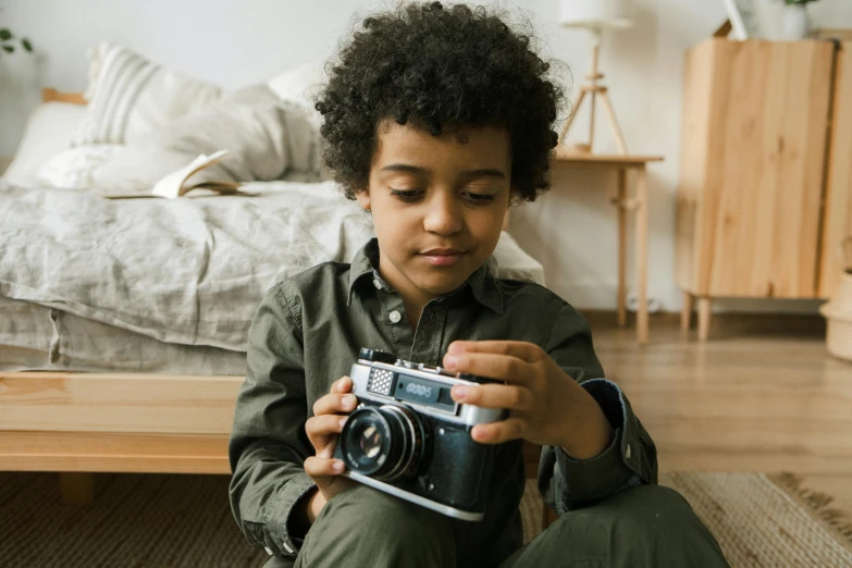 a boy sitting on the floor with a camera