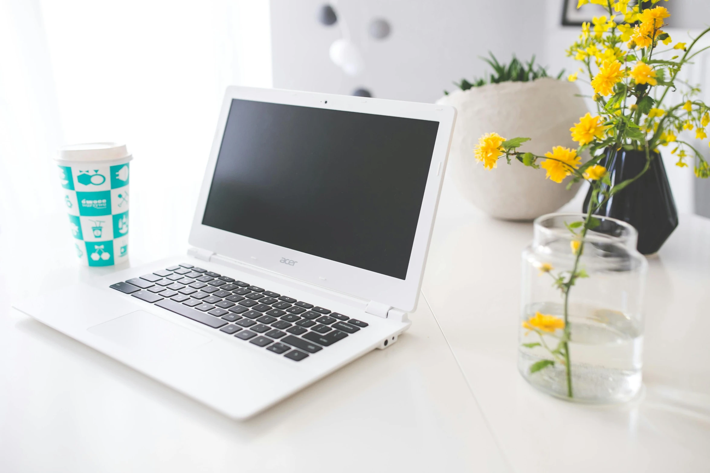 there is a vase of flowers next to a laptop