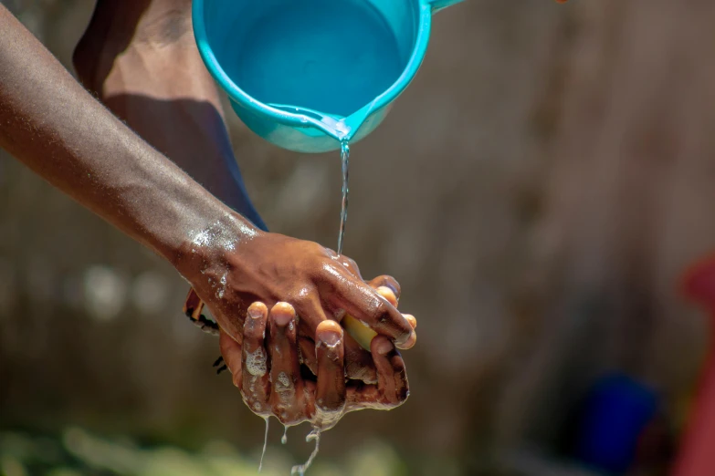 the person holds a blue plastic bowl over a body of water