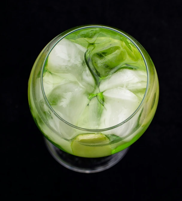 a glass filled with green drinks and ice