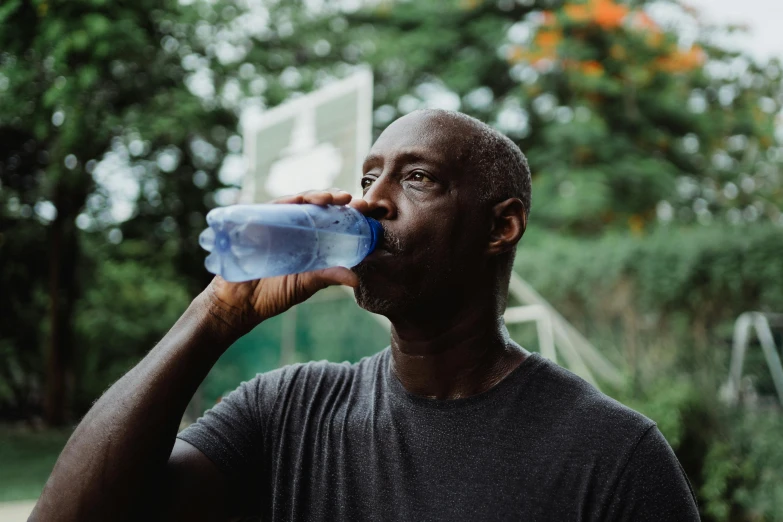 a man drinking water out of a plastic bottle