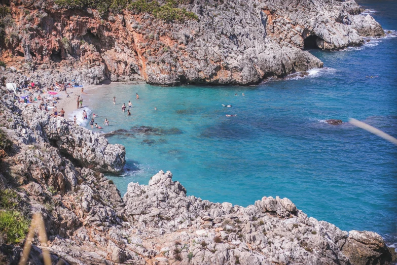 many people are standing on the edge of a cliff by the ocean