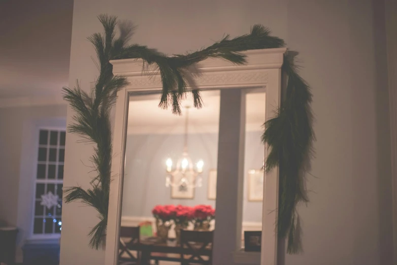 this is a mirror decorated with evergreen nches and lights