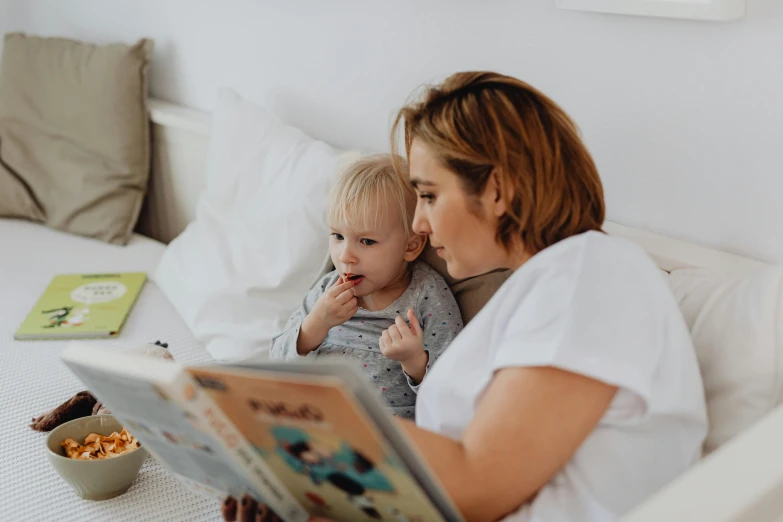 a mother reading her child a storybook in bed